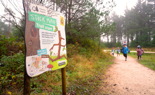 Children running towards a Stick Man activity trail panel