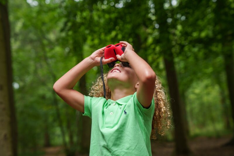 A child looking up through binoculars