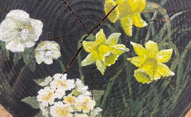 Painting of daffodils on a log slice