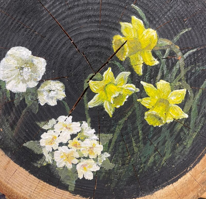 Painting of daffodils on a log slice