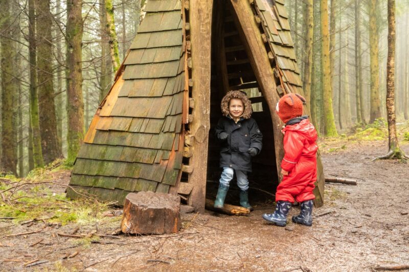 Two children playing in a wooden den