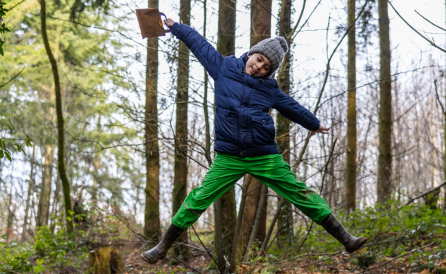 A child jumping in the air in a forest