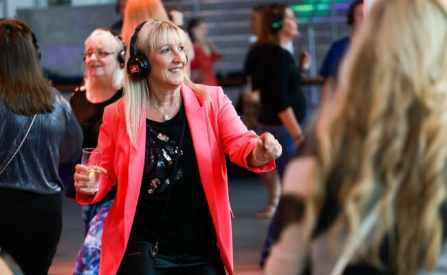 Photograph showing a woman dancing with headphones on