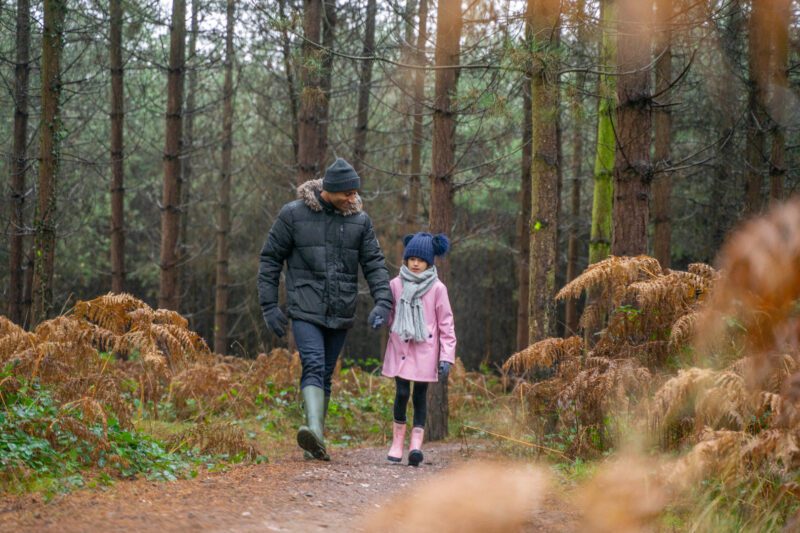 Adult and child walking on a forest trail